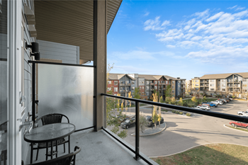 a balcony with a table and chairs and a view of a parking lot